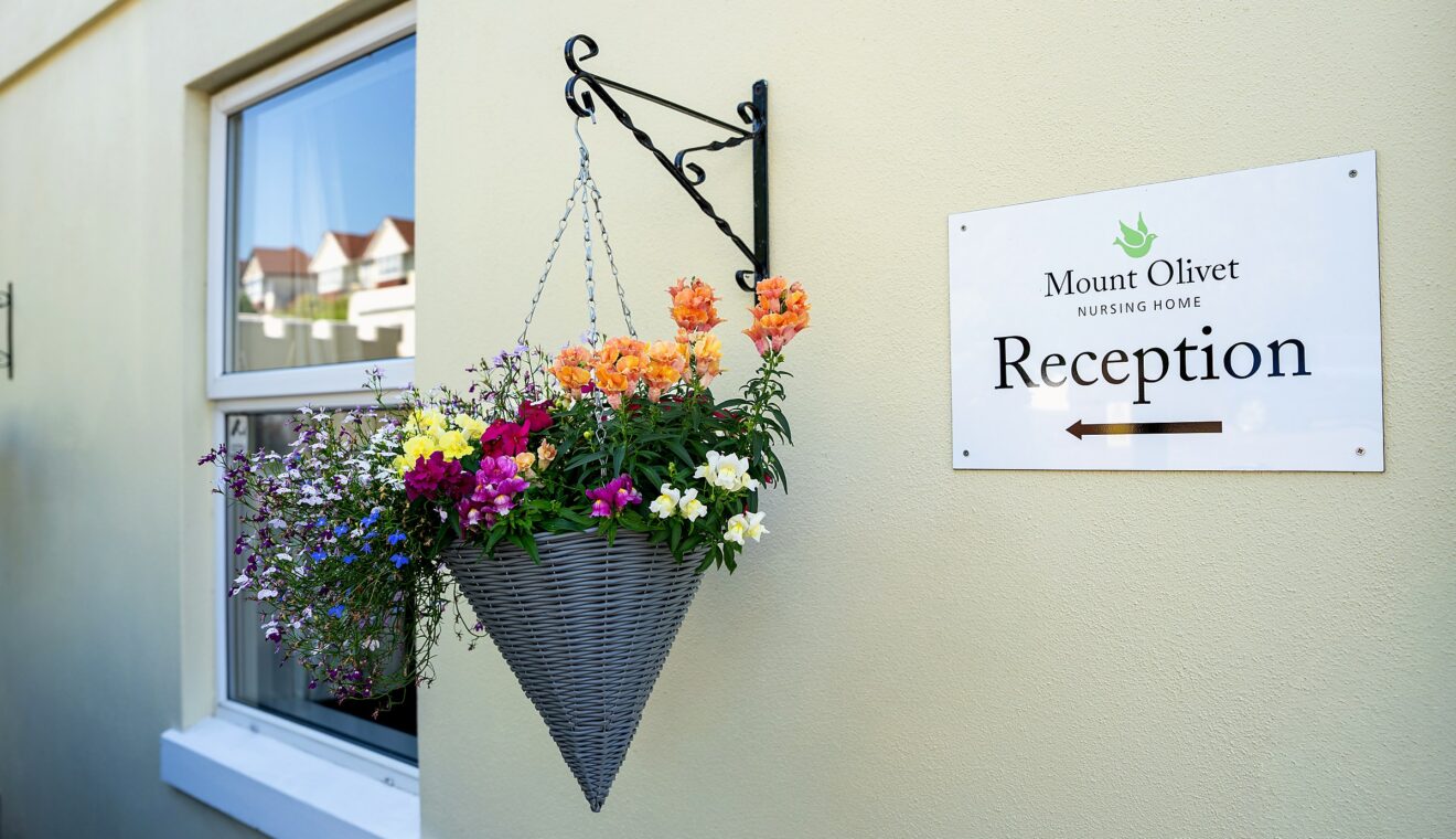 A hanging flower basket beside the Reception sign at Mount Olivet's entrance