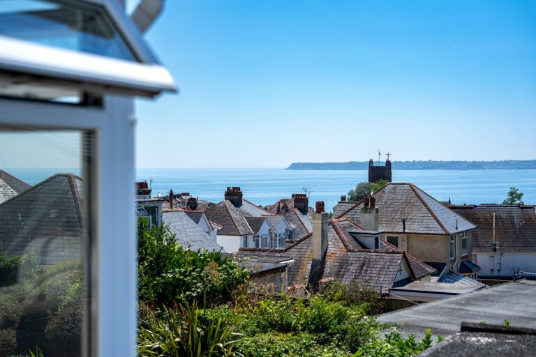 Sea view across Torbay from Mount Olivet, with rooftops and a church tower in the foreground