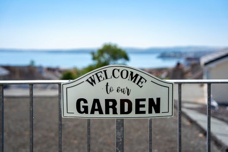 A 'Welcome to our Garden' sign on the balcony railing, with Torbay in the background