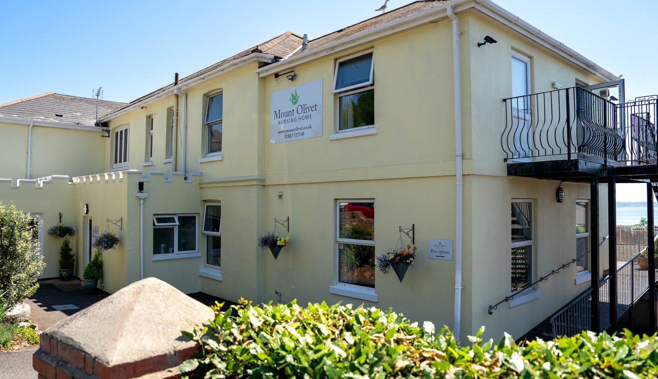 Mount Olivet Nursing Home's entrance and driveway, with hanging baskets either side of the door