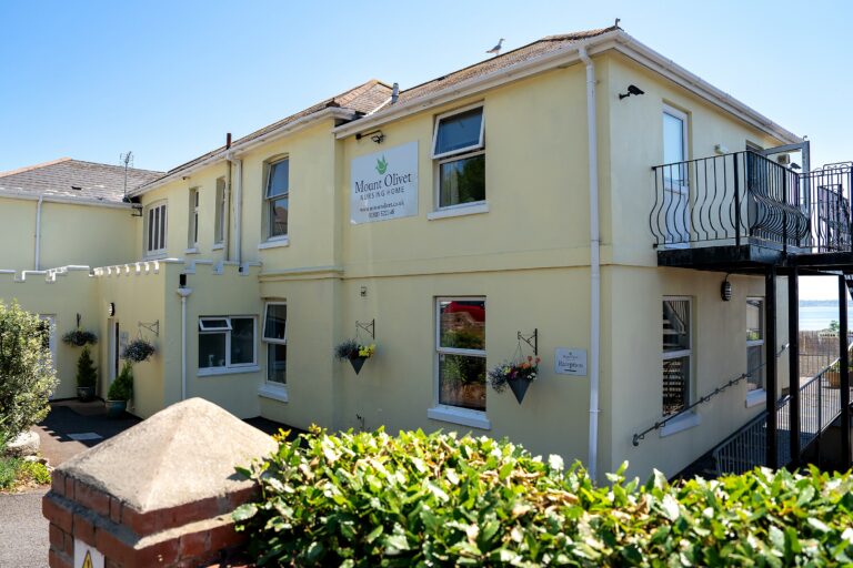 Mount Olivet Nursing Home's entrance and driveway, with hanging baskets either side of the door