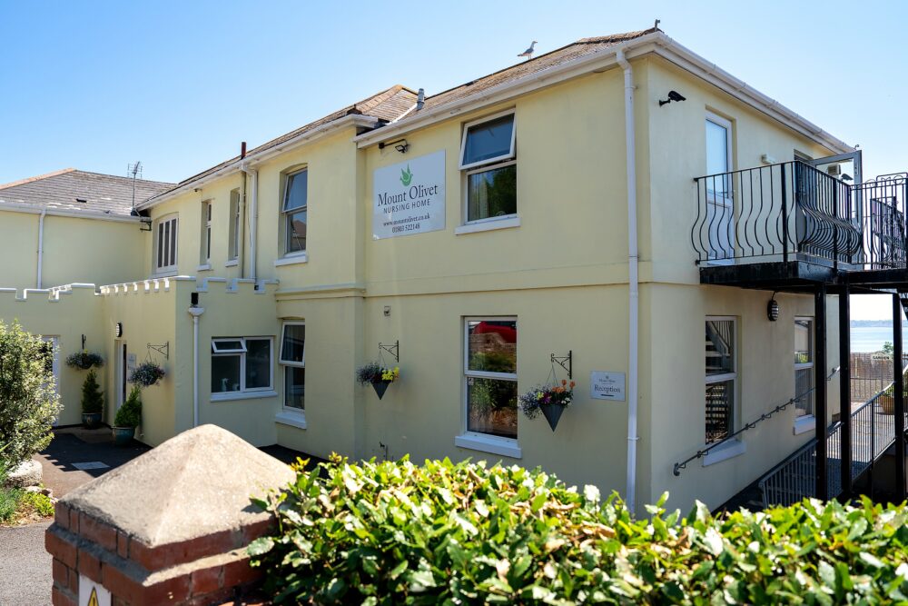Mount Olivet Nursing Home's entrance and driveway, with hanging baskets either side of the door