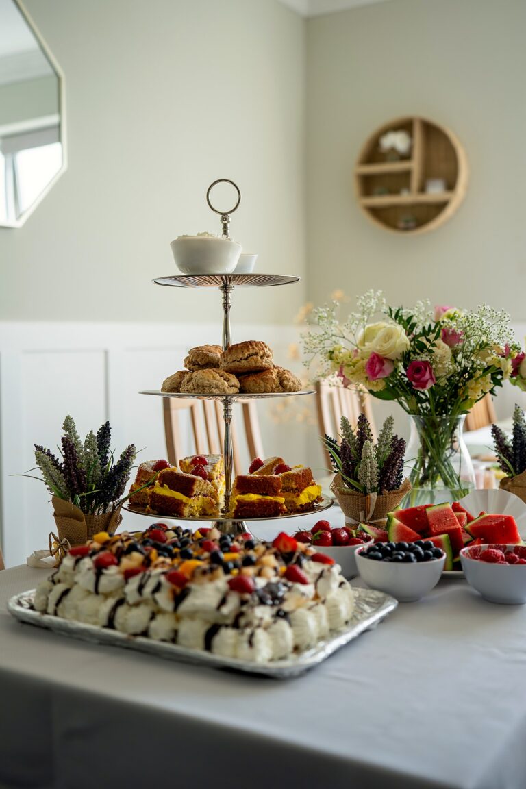 A three-tier cake stand of scones, sponge cake and pavlova, served for afternoon tea