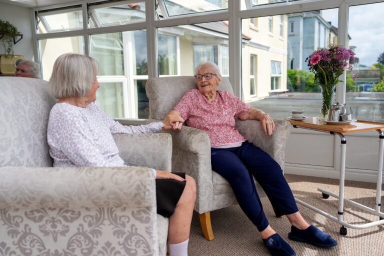 A staff member and resident chatting together in the conservatory