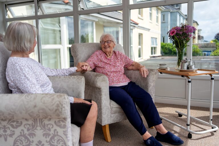 A staff member and resident sharing a moment in the conservatory