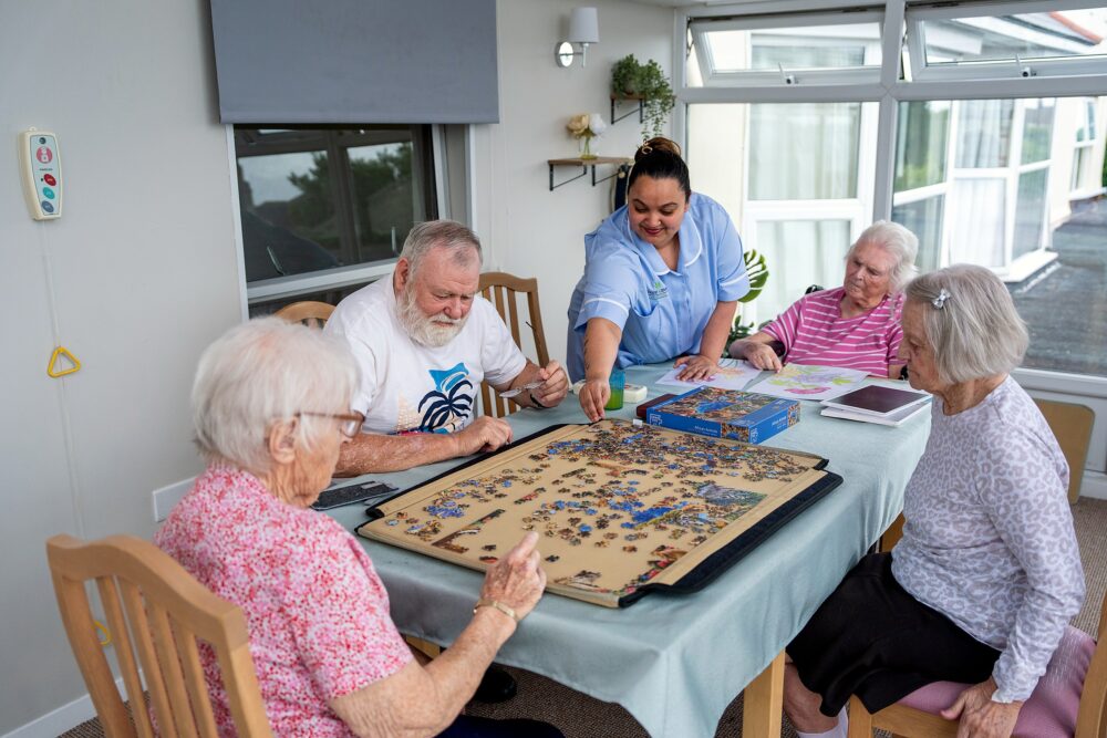 A staff member supporting a resident with a colouring activity