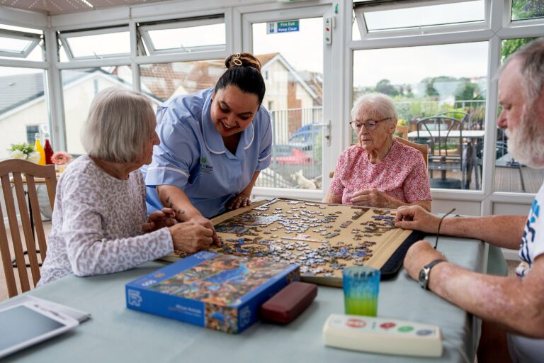 Residents and staff gathered around a jigsaw puzzle