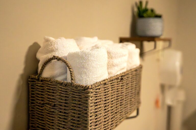 Freshly rolled towels in a wall-mounted basket in an en-suite bathroom