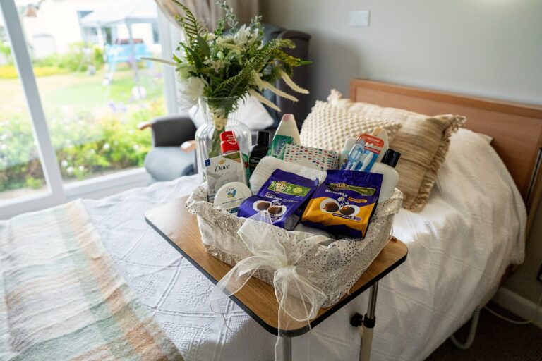 A welcome basket of toiletries and treats laid out on a resident's bed